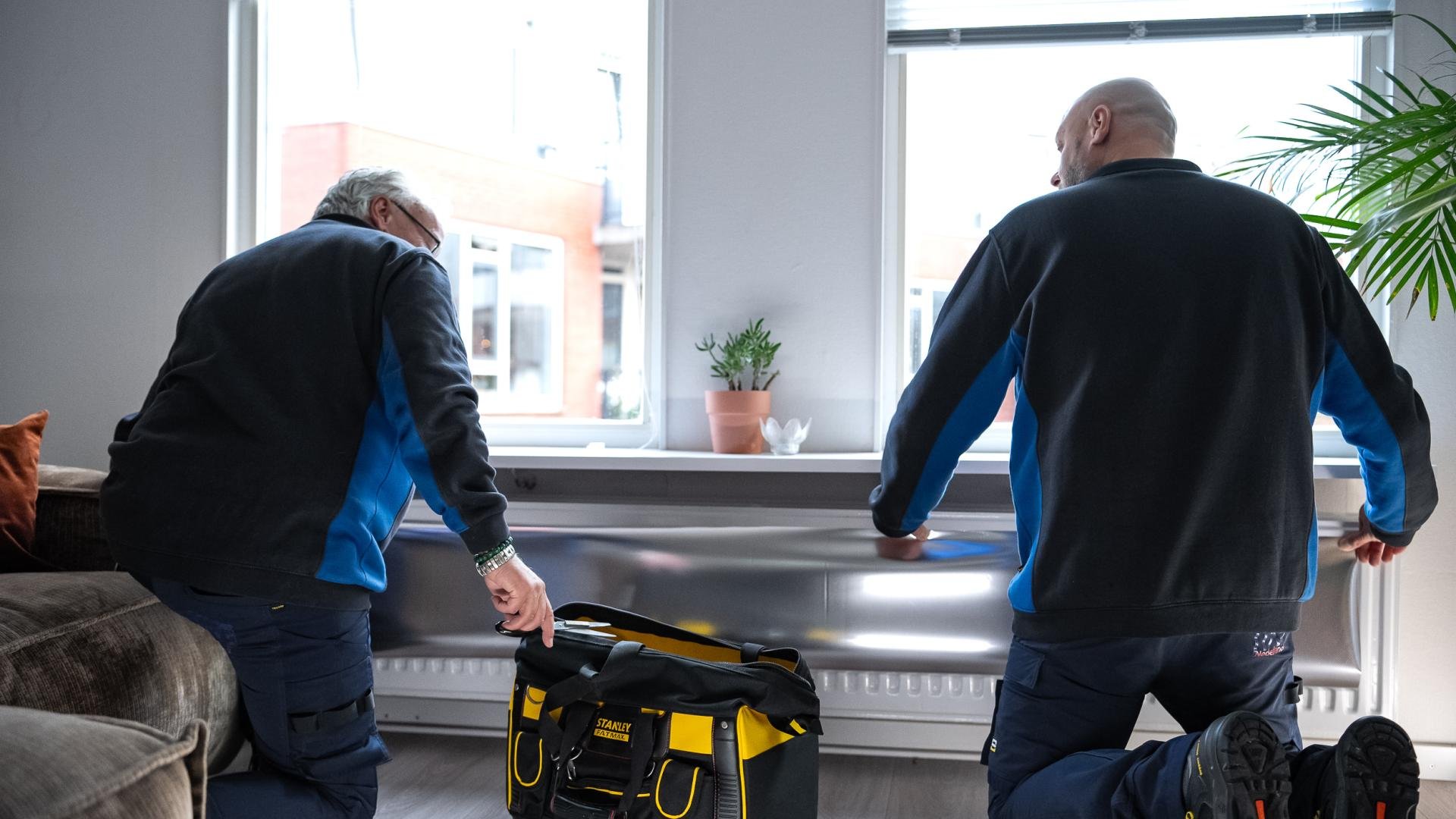 Mannen van de FIXbrigade brengen radiatorfolie aan.